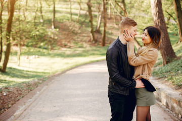 Cute couple in a park. Lady in a brown jacket.