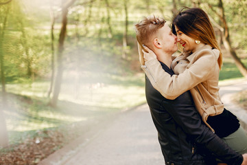 Cute couple in a park. Lady in a brown jacket.
