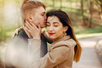 Cute couple in a park. Lady in a brown jacket.