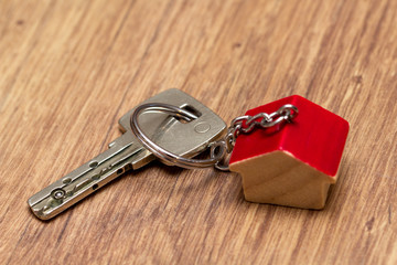 Schlüssel mit Schlüsselanhänger in Haus Form liegt auf Holz