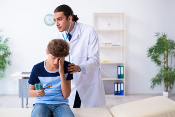 Young male doctor examining boy in the clinic