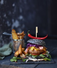 black buns burger with red cabbage, cheese and bacon.. Cheeseburger from Japan with black bun on dark background. 