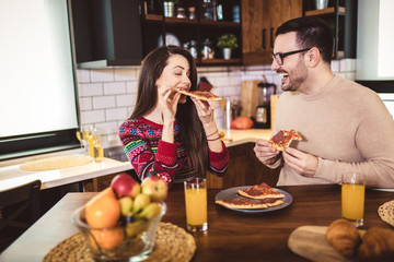 Young couple enjoying eating pizza at home.