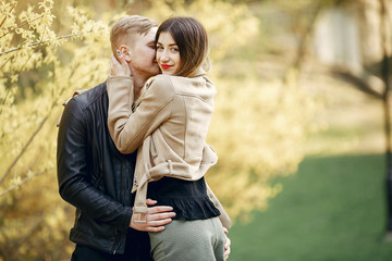 Cute couple in a park. Lady in a brown jacket.