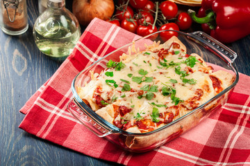 Traditional mexican enchiladas with chicken meat, spicy tomato sauce and cheese in heat resistant dish
