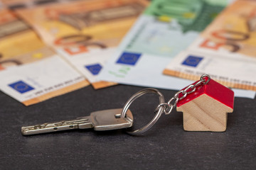 Schlüsselbund mit Geldscheinen auf Schiefertafel