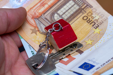 Schlüsselbund mit Schlüsselanhänger liegt auf Geldscheinen