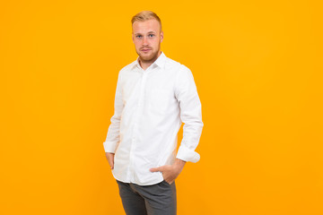 portrait of a blond young man in a white shirt on a yellow background with copy space