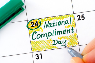 Woman fingers with pen writing reminder National Compliment Day in calendar. - Powered by Adobe