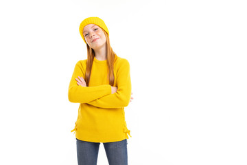 Happy teenager girl with red hair, yellow hoody and trousers thinks about something good isolated on white background