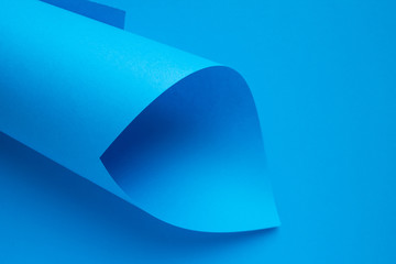 Rolled up roll of bright blue paper on a monochrome background close up with space for copying