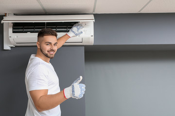 Male technician repairing air conditioner indoors