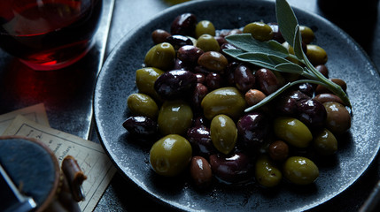 Small plate of grean and black olives with sage leaf garnish