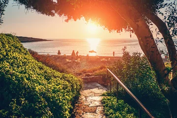 Photo sur Plexiglas Chypre Paysage de Chypre. Descente le long d& 39 un chemin pavé jusqu& 39 à la plage et la mer au coucher du soleil. Concept de vacances méditerranéennes.