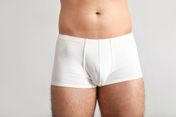 Young man in underwear on light background