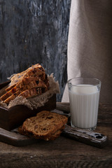 A glass of fresh milk and pieces of rye bread on a wooden table.