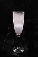 A glass glass glass for champagne filled with smoke on a black background.