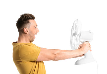 Young man with electric fan on white background