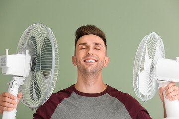 Fototapeta Young man with electric fans on color background obraz