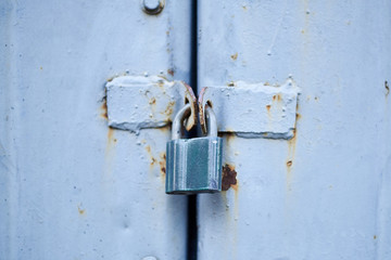 Old metal doors are closed on a padlock.