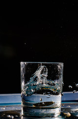 Multicolored splashes of summer. Fresh fruit and splashes of water.The photo shows a slice of green apple thrown into a glass of water. Splashes of cool drink refresh.
