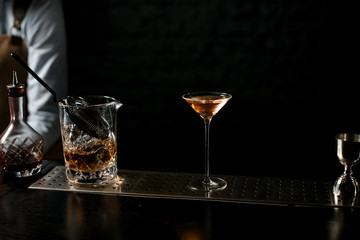 Professional bartender serving a little martini glass full of delicious golden cocktail