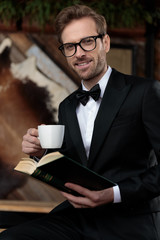 Happy fashion model smiling, holding a coffee cup and book