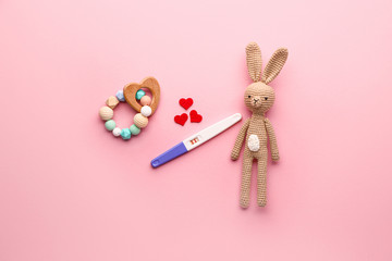Pregnancy test and toys on color background