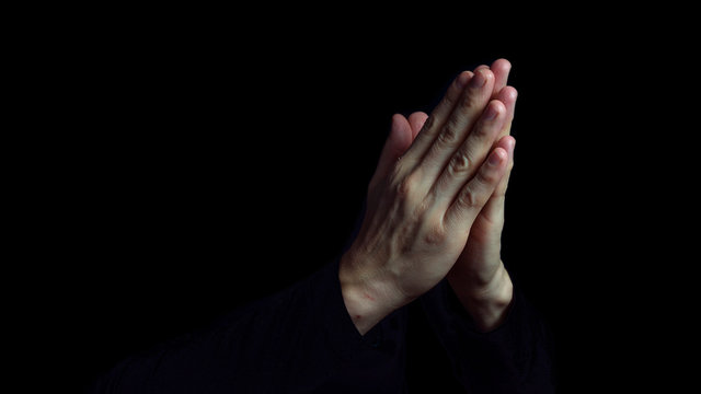 Man Praying Hands in black background. Close up.