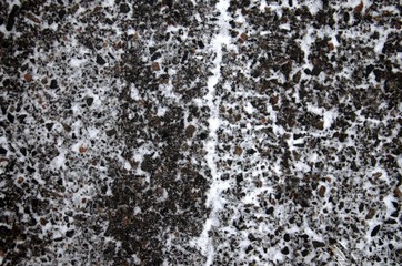 The black asphalt is covered with snow. Close up. Snow on the road surface.