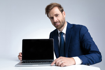 Handsome businessman presenting his laptop while wearing a blue suit