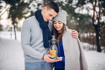 Couple in a winter forest. Beautiful girl in a blue sweater. Boy and girl with candle