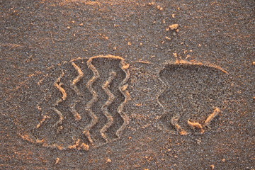 Huella de zapato en la arena de la playa con luz de puesta de sol.