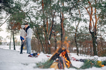 Couple in a winter forest. Beautiful girl in a blue sweater. Boy and girl near bonfire