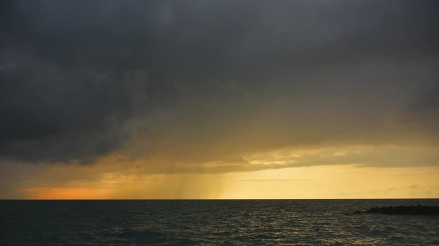 Golden sunset over the sea in cloudy rainy weather. Seascape. Time-lapse movie in 4k quality.