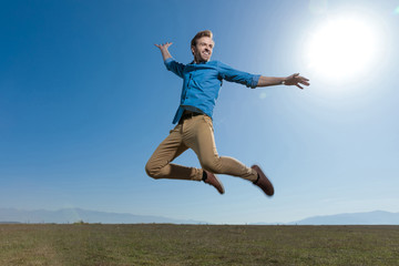  casual man wearing blue shirt jumping high to the sky