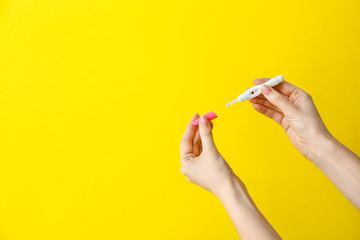 Female hands with pregnancy test on color background