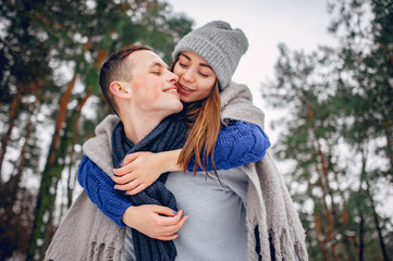 Fototapeta premium Couple in a winter forest. Beautiful girl in a blue sweater.