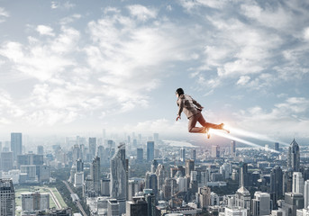 Businessman in suit and aviator hat flying in sky