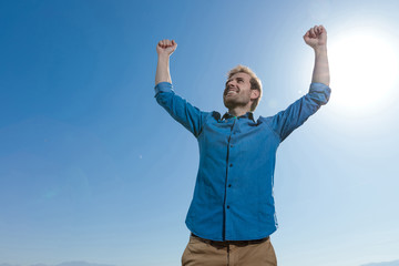 young casual man wearing blue shirt celebrating succes