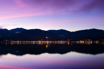 The beautiful lake Tegernsee in the south of bavaria, germany, with mountains and a small town in the background at the blue hour and nice reflections