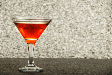 Whiskey with ice or brandy in a glass on a rustic table and gray background. Whiskey with ice in a glass. Whiskey or cognac in a glass. Selective focus.