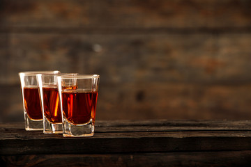 Whiskey with ice or brandy in a glass on a rustic background. Whiskey with ice in a glass. Whiskey or brandy. Selective focus.