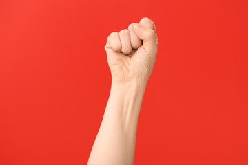 Hand of woman with clenched fist on color background