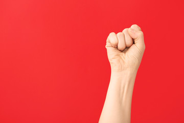 Hand of woman with clenched fist on color background