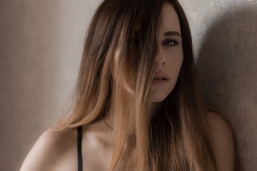 Naklejka premium Portrait of a woman.Beautiful girl with bare shoulders, sexy look from under a lock of hair.Dramatic image, close-up