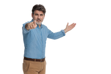 Motivated casual man presenting and pointing forward