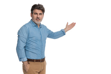 Friendly casual man presenting with a hand in his pocket