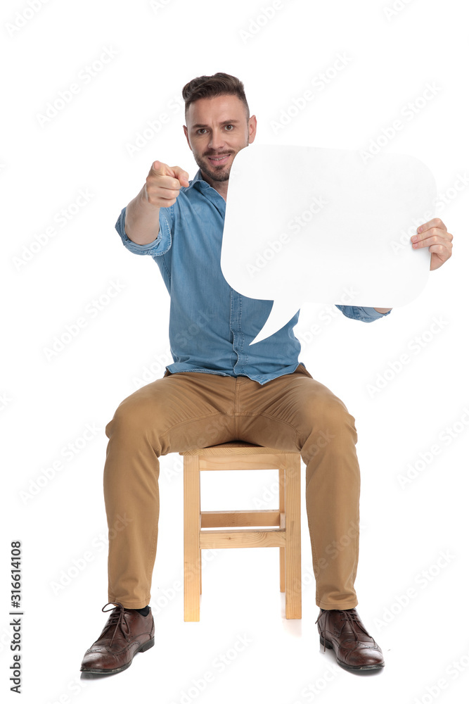 Canvas Prints young casual man holding speech bubble and pointing finger