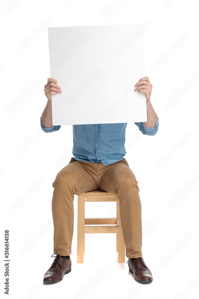 Canvas Prints young casual guy hiding behind empty board